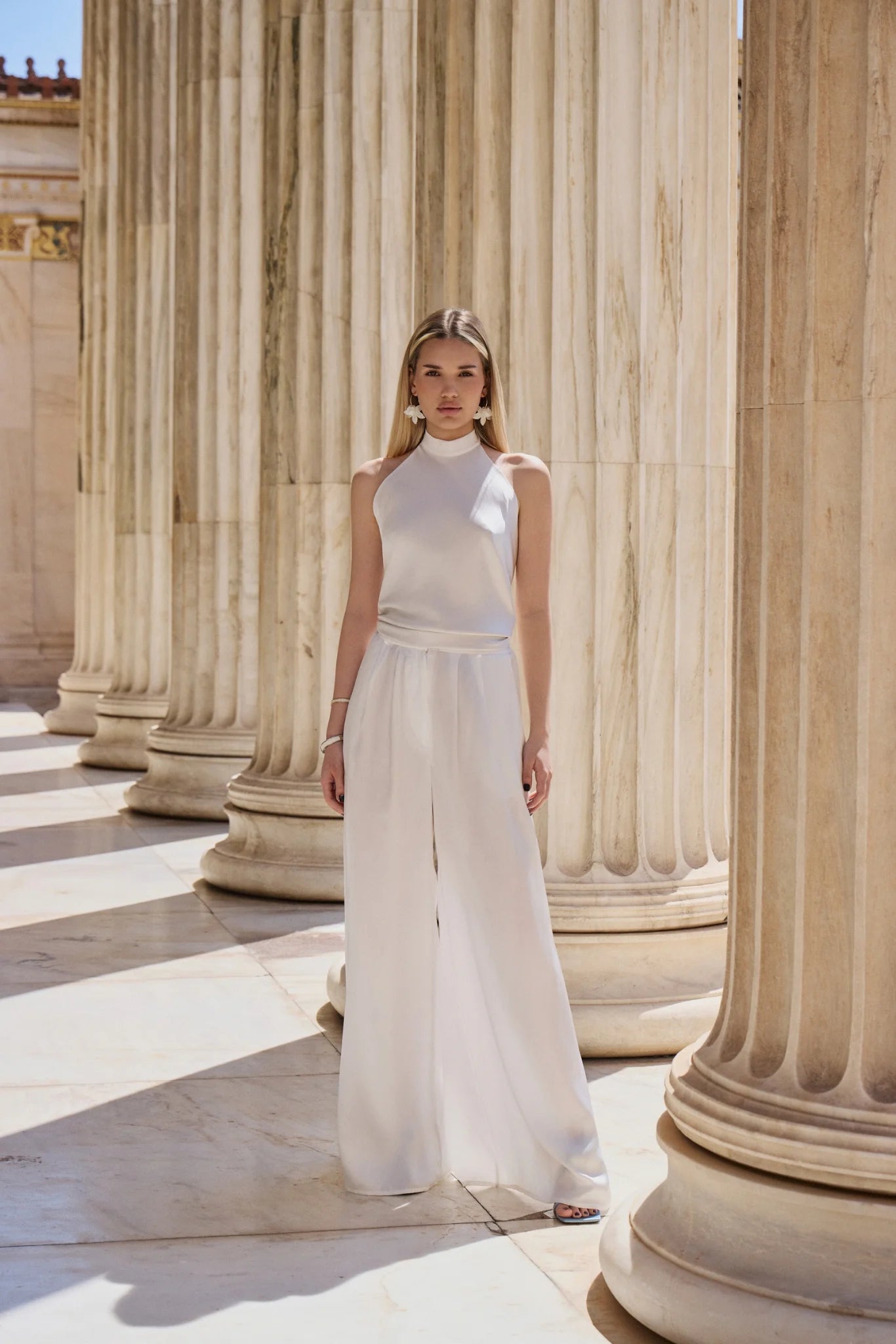 Woman in a white dress standing among ancient columns